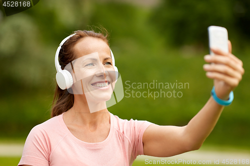 Image of woman in phones takes selfie by smartphone at park