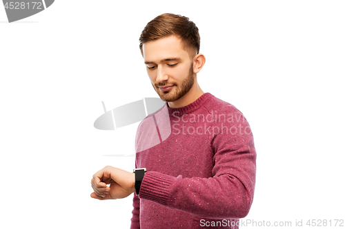 Image of smiling young man checking time on wristwatch