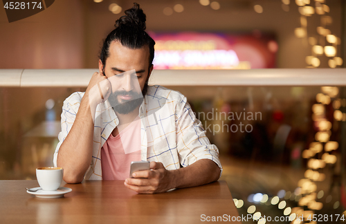 Image of man with coffee and smartphone at restaurant