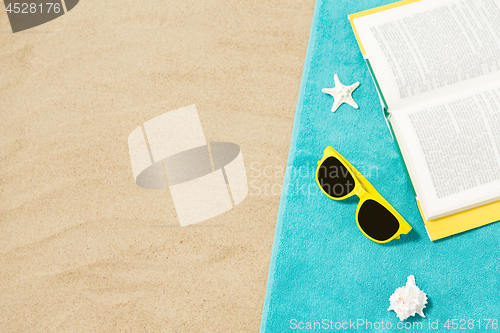 Image of sunglasses and book on beach towel on sand