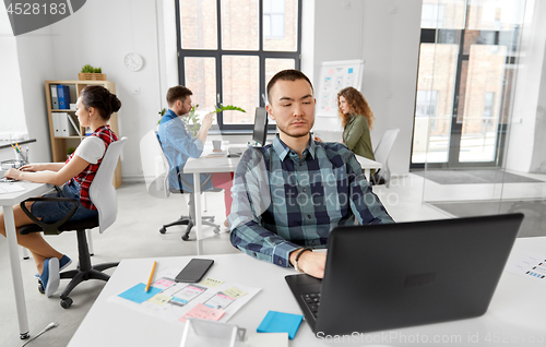 Image of creative man with laptop working at office