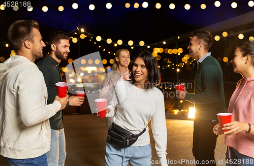 Image of friends with drinks dancing at rooftop party