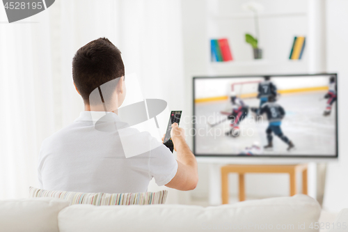 Image of man watching ice hockey game on tv at home