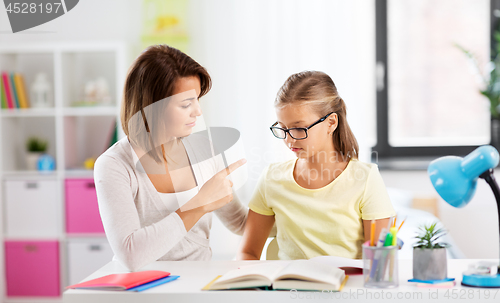 Image of strict mother talking to daughter doing homework