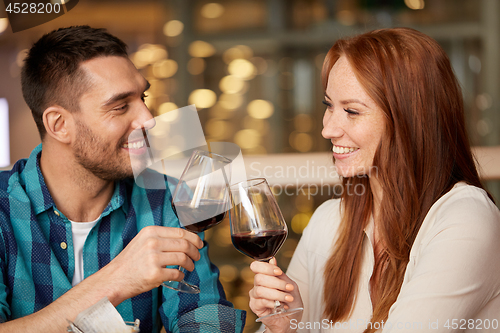 Image of happy couple drinking red wine at restaurant