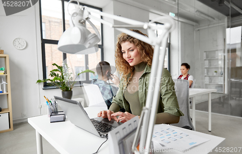 Image of creative woman with laptop working at office