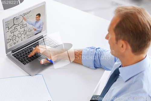 Image of businessman watching webinar on laptop at office