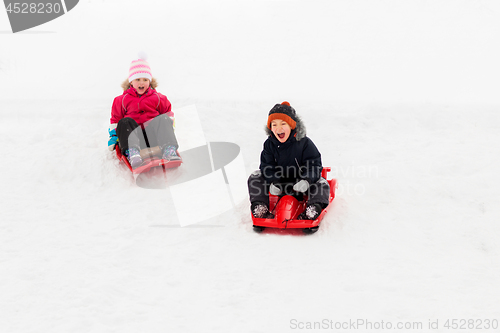 Image of happy kids sliding on sleds down hill in winter