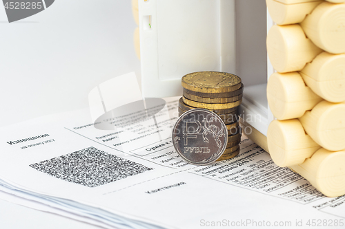 Image of A stack of money and one ruble coin in the accounts for the apartment, in front of the door to the house