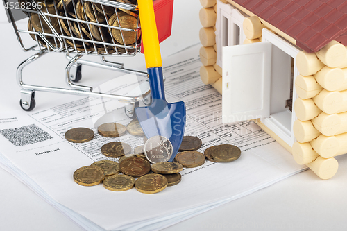 Image of A shovel with a ruble coin rests on a money cart, a number of apartment bills and a toy house