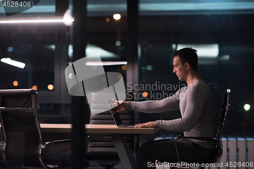 Image of man working on laptop in dark office