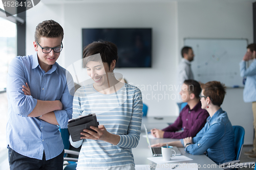 Image of Two Business People Working With Tablet in office