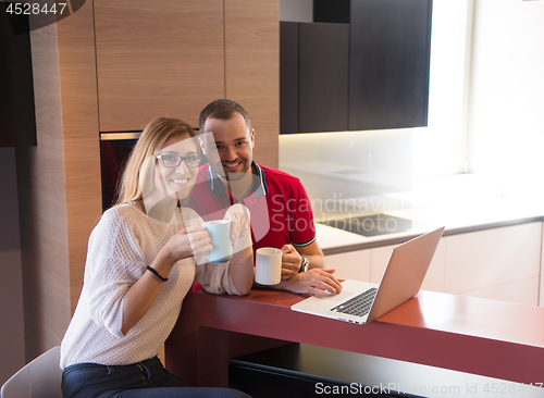 Image of couple drinking coffee and using laptop at home