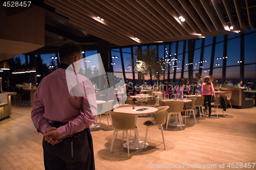 Image of waiter standing with hands behind his back