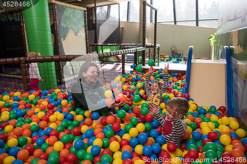 Image of Young mom with her kids in a children\'s playroom