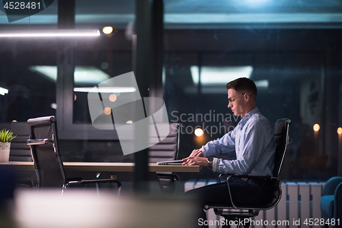 Image of man working on laptop in dark office