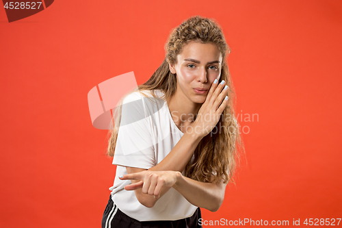 Image of The young woman whispering a secret behind her hand