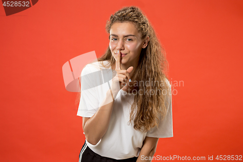 Image of The young woman whispering a secret behind her hand