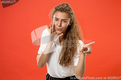 Image of The young woman whispering a secret behind her hand