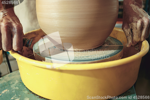 Image of Creating a jar or vase of white clay close-up. Master crock.