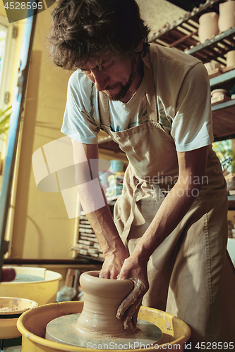 Image of Creating a jar or vase of white clay close-up. Master crock.