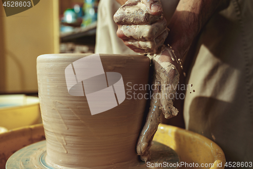 Image of Creating a jar or vase of white clay close-up. Master crock.