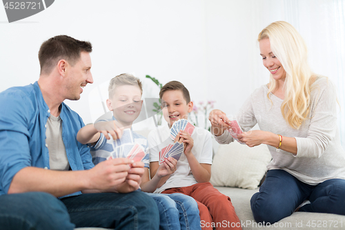 Image of Happy young family playing card game at home.