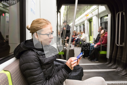 Image of Young girl reading from mobile phone screen in metro.