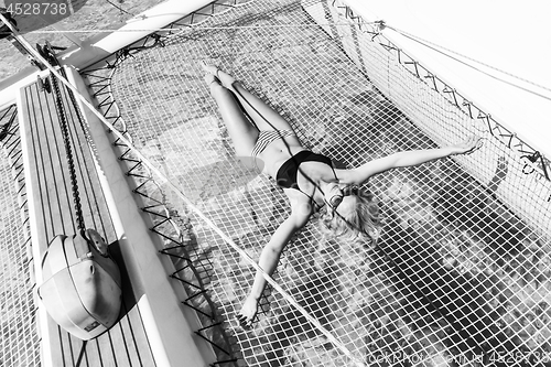 Image of Womanin bikini tanning and relaxing on a summer sailin cruise, lying in hammock of luxury catamaran boat.