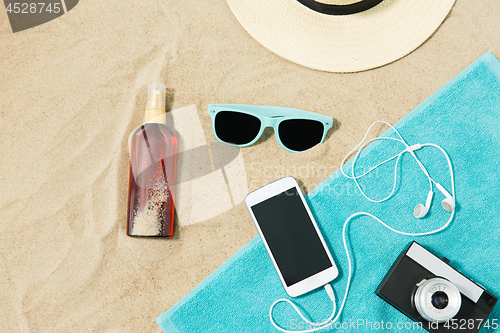 Image of smartphone, camera, towel, hat and shades on beach