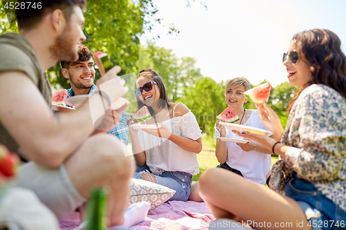 Image of happy friends eating watermelon at summer picnic