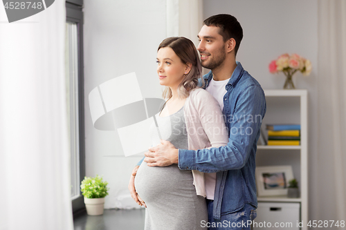 Image of man hugging pregnant woman at window at home