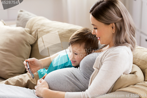 Image of pregnant mother and son with smartphone at home