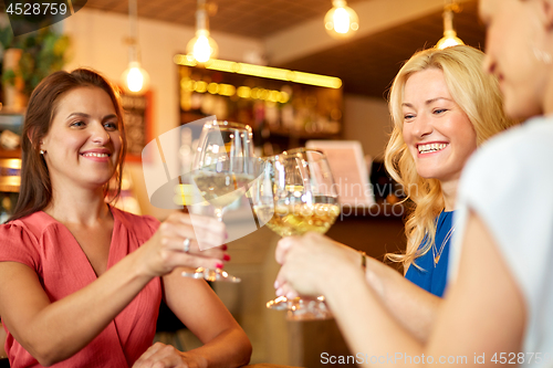 Image of happy women drinking wine at bar or restaurant