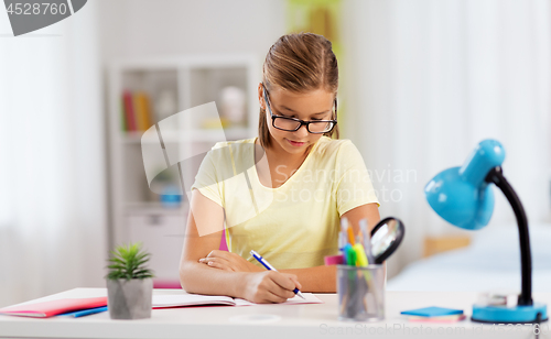 Image of student girl writing to notebook at home