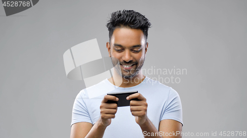 Image of happy indian man playing game on smartphone
