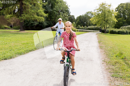 Image of grandmother and granddaughter cycling at park