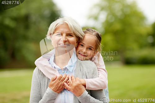 Image of granddaughter hugging grandmother at summer park