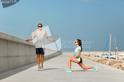 Image of happy couple warming up on pier before training