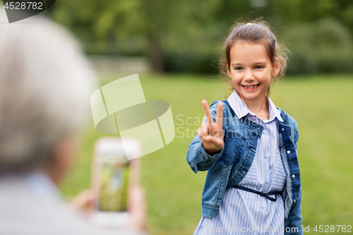 Image of girl being photographed and showing peace sign