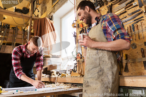 Image of carpenters with ruler and coffee at workshop