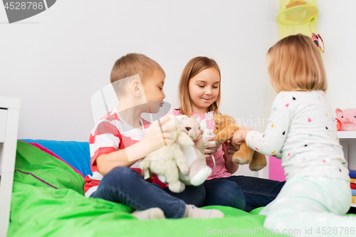 Image of happy children playing with soft toys at home