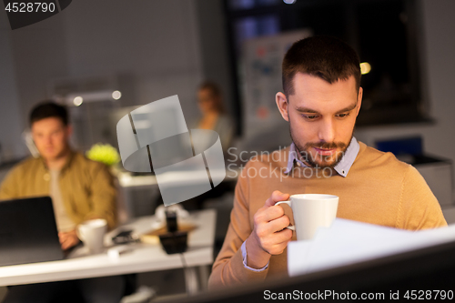 Image of happy male office worker drinking coffee