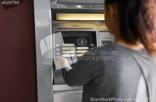 Image of woman at atm machine with bitcoin icon on screen