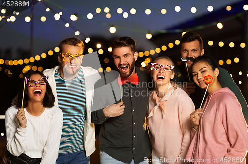 Image of happy friends with party props at rooftop