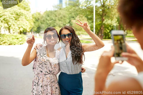 Image of woman photographing her friends in summer park