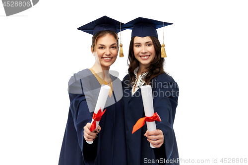 Image of female graduates in mortar boards with diplomas