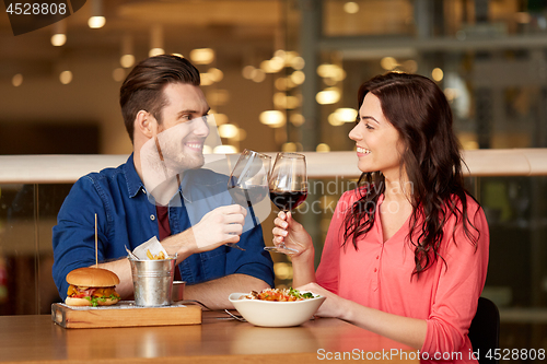 Image of couple eating and drinking red wine at restaurant