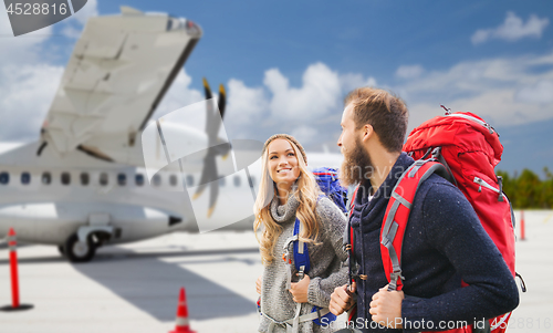 Image of couple of tourists with backpacks over plane