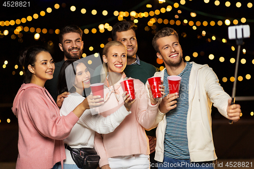 Image of friends with drinks taking selfie at rooftop party